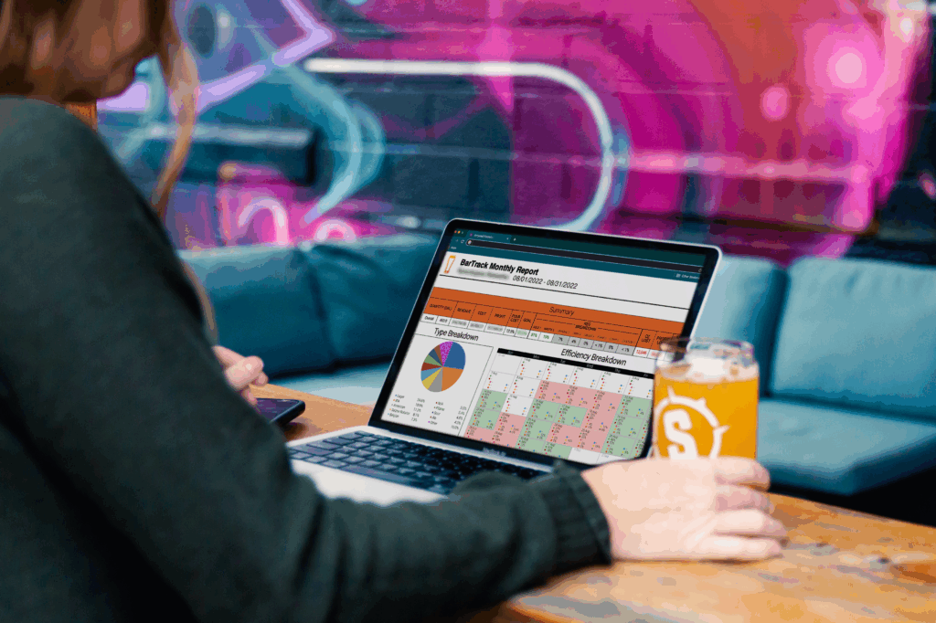 person sitting at a bar working on a computer with a beer in hand